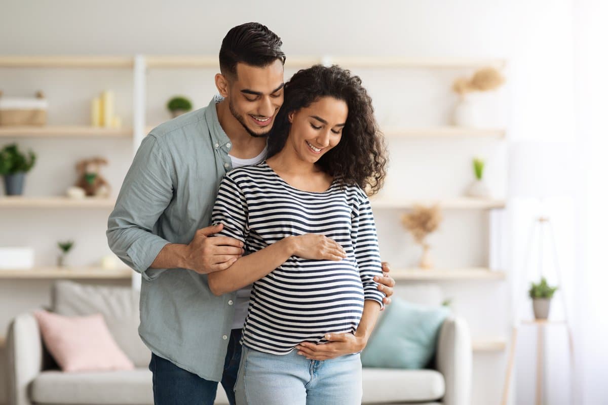 Couple attendant un bébé, mains posées sur le ventre de la future maman