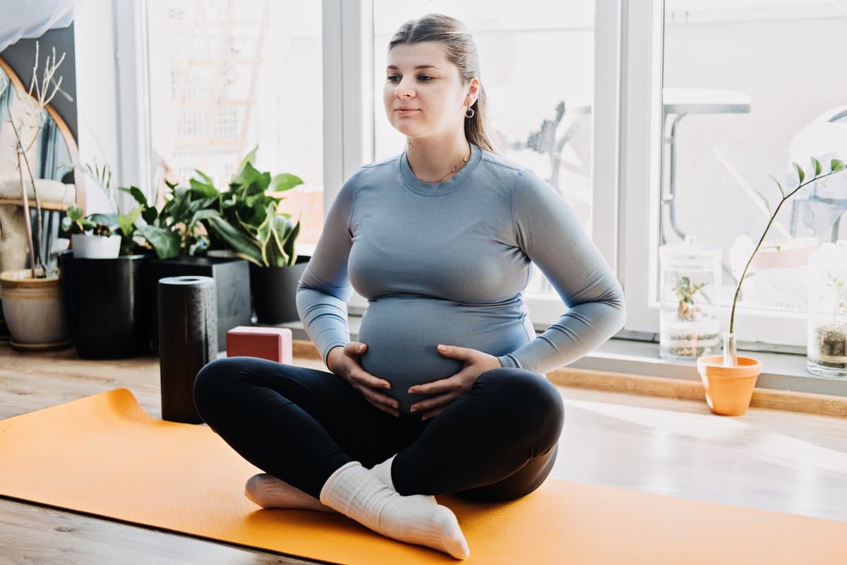 Femme enceinte faisant des exercices doux sur un tapis